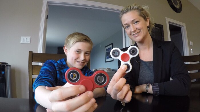 Une dame et son fils montrent des toupies « Hand Spinners »