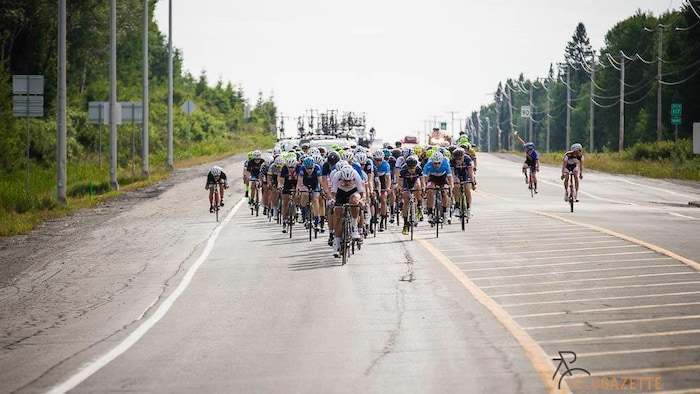 Un peloton de cyclistes sur la route 117 lors du 49e Tour de l'Abitibi