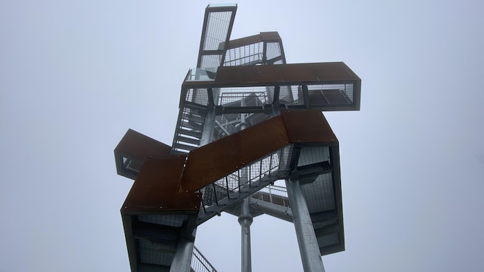 La tour, vue du bas, est dans un épais brouillard. 