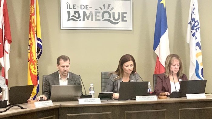 Trois personnes assises dans une salle.