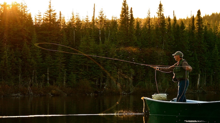 Un pêcheur lance un filet debout sur son canot.