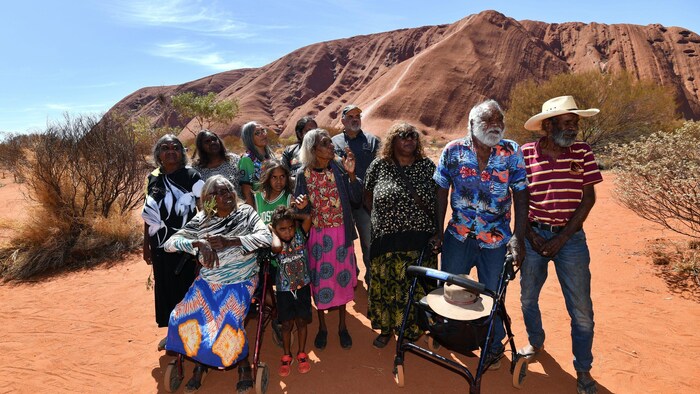 Une famille aborigène au grand complet pose devant le rocher.