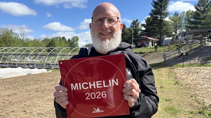 Un homme tient une plaque sur laquelle est écrite « Michelin, 2026 »