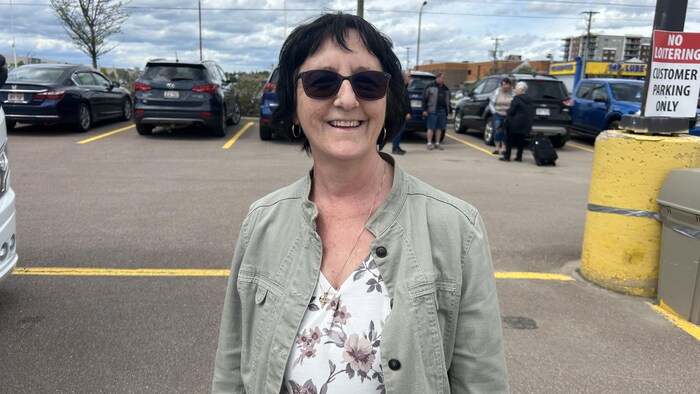 Une femme debout dans un stationnement. 