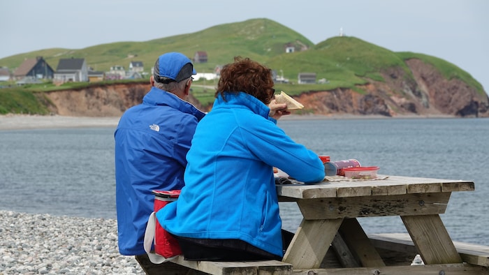 Un couple mange sur une table à pique-nique devant les buttes des Demoiselles sur le site de La Grave.