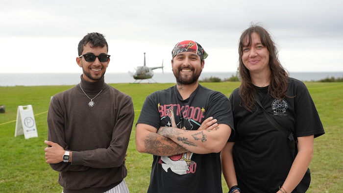 Trois touristes à Percé devant un hélicoptère.