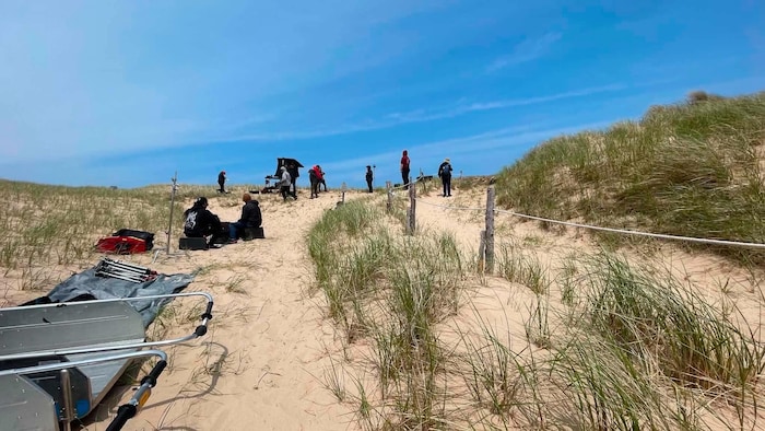 Des personnes avec des équipements dans des dunes.