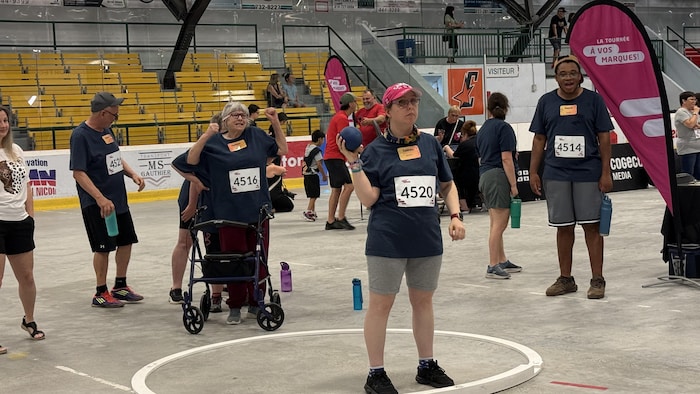 Une participante tient un poids d'athlétisme dans ses mains et se prépare à le lancer.