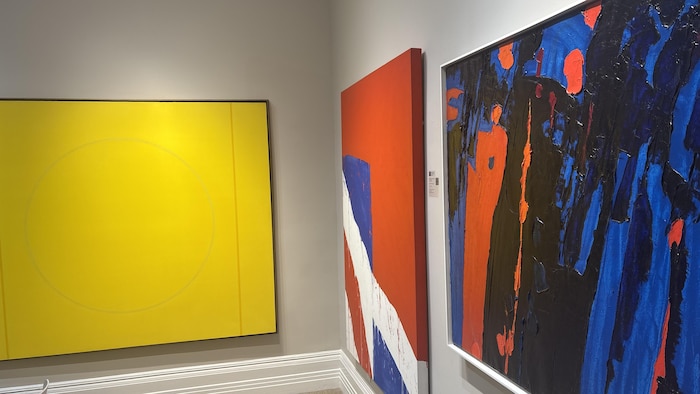 Trois toiles colorées sont exposées dans une galerie.