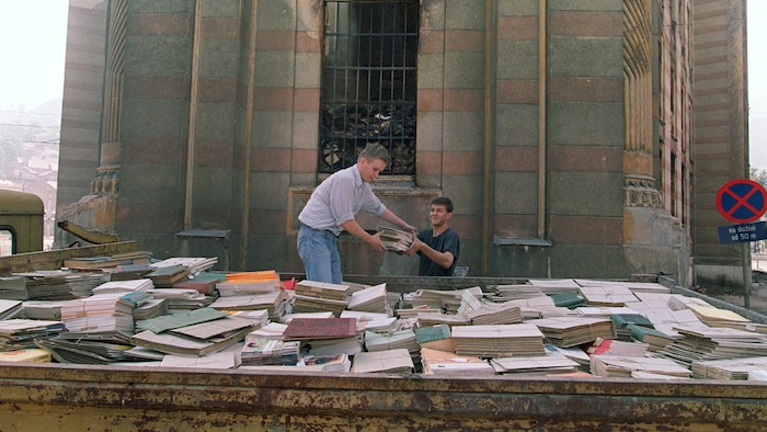  Des habitants de Sarajevo tentent de sauver quelques livres du sous-sol de la Bibliothèque nationale de Sarajevo, le 29 août 1992.