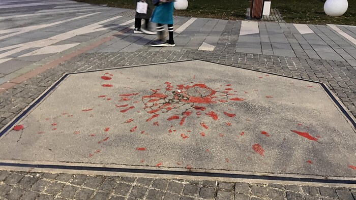 Des traces d'obus sur le pavé, remplies de peinture rouge.