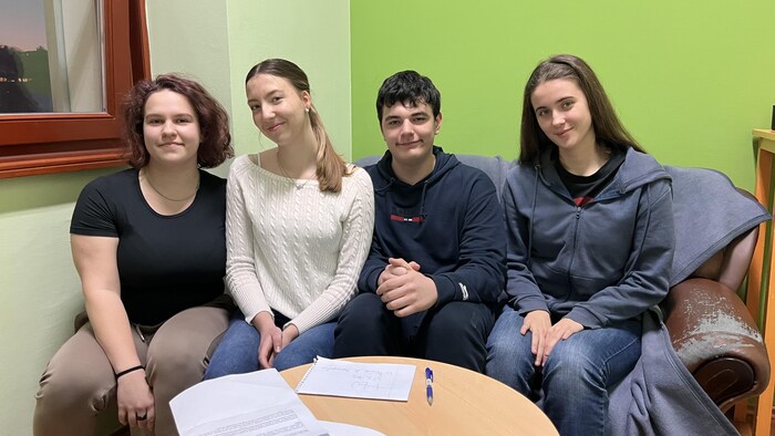 Quatre jeunes assis sur un canapé devant une petite table.