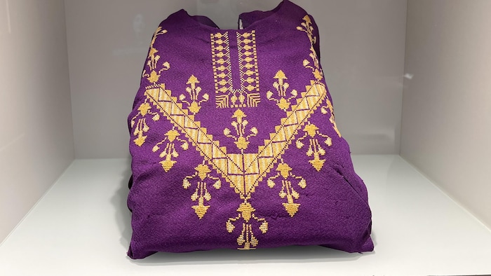 Une robe violette brodée de fils jaunes pliée.