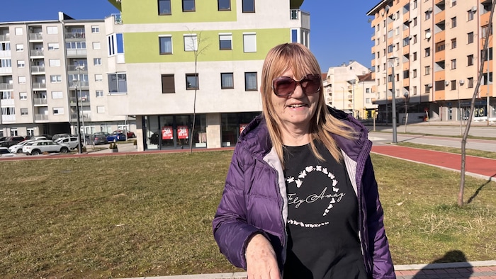 Une femme serbe devant des immeubles résidentiels.