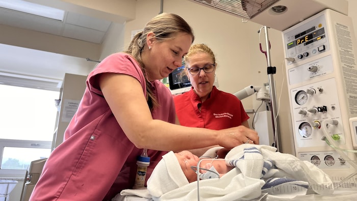 L'infirmière Karina Bond Desharnais et la gynécologue Isabelle Bossé sont penchées sur un nouveau-né.