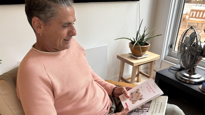 Un homme assis sur une chaise tenant deux livres dans ses mains.