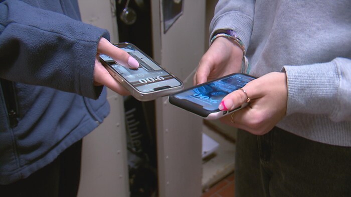 Deux étudiants tiennent leur téléphone cellulaire. 