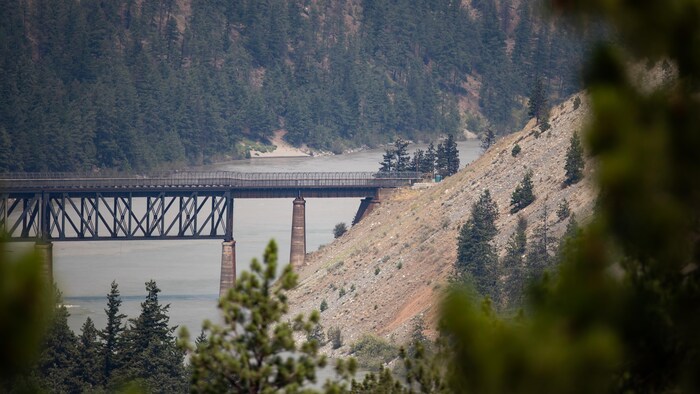 Un pont ferroviaire enjambe le fleuve Fraser alors qu'un feu de forêt brûle à Lytton, en Colombie-Britannique.