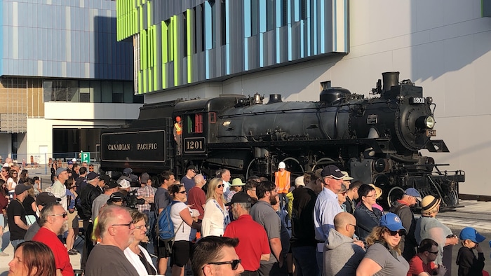 Des gens rassemblés au Musée canadien de la science et de la technologie, devant la locomotive CP 1201.