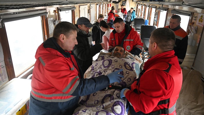 Une équipe médicale s'occupe d'un patient à bord d'un train.