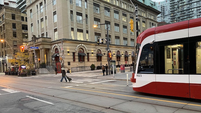 Des piétons traversent devant un tramway. 