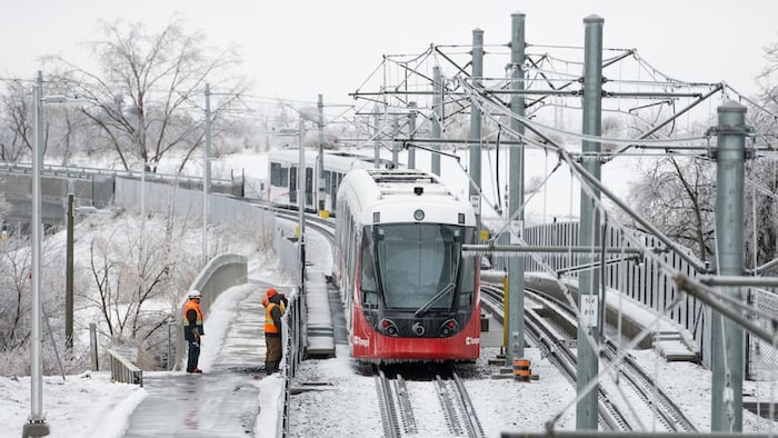 Des agents d'entretien près du tramway OC Transpo tombé en panne après avoir subi une panne d'électricité.