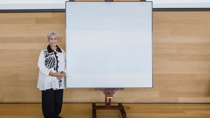 Une femme aux côtés d'un tableau artistique.