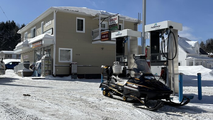 Un motoneige en train de se ravitailler à un poste d'essence.