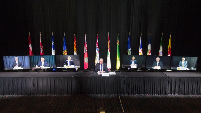 François Legault est assis derrière une table. Autour de lui, des téléviseurs diffusent l'image de ses homologues provinciaux : John Horgan, Jason Kenney, Scott Moe, Brian Pallister, Doug Ford et Blaine Higgs.
