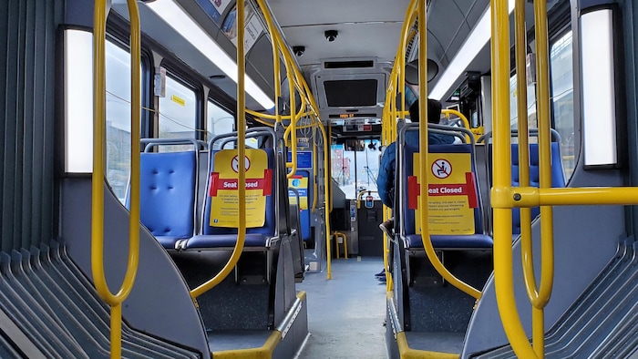 L'intérieur d'un autobus avec des affiches sur certains sièges stipulant qu'ils ne sont pas accessibles.