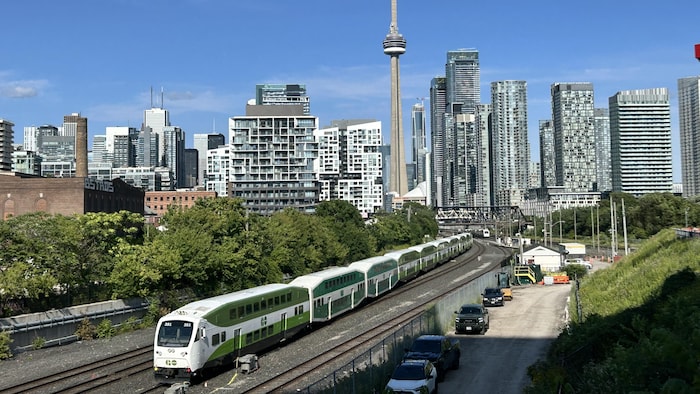 Un train GO et le centre-ville de Toronto en arrière-plan.