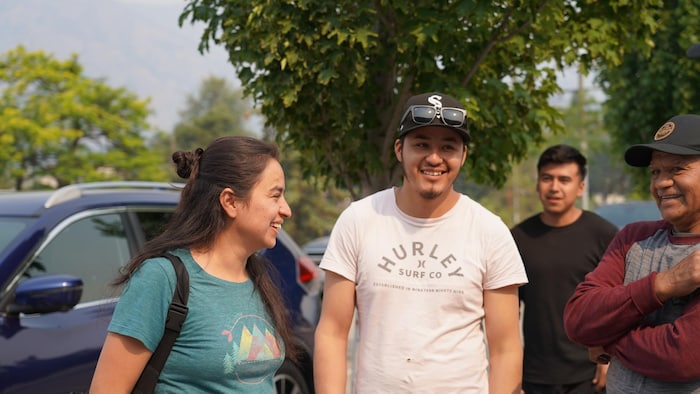 Des personnes mexicaines se parlent entre elles devant des voiture stationnées.