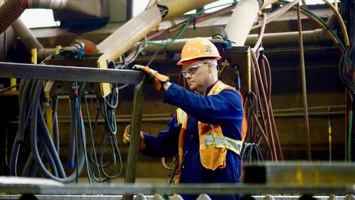 Un travailleur manipule un cadre en acier.                       