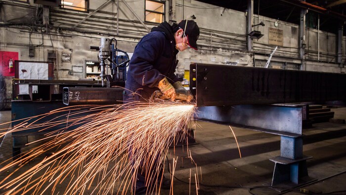 Un travailleur polit une pièce d'acier dans une aciérie de Colombie-Britannique.