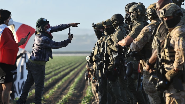 Des manifestants devant une rangée d'agents.