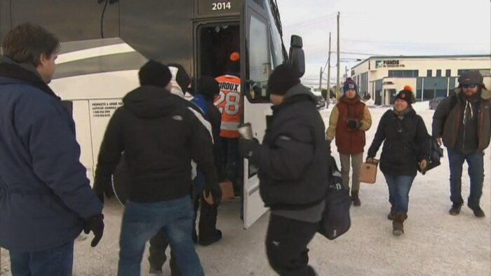 Des travailleurs d'Alma montent dans un autobus