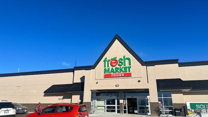 Des véhicules devant une épicerie.