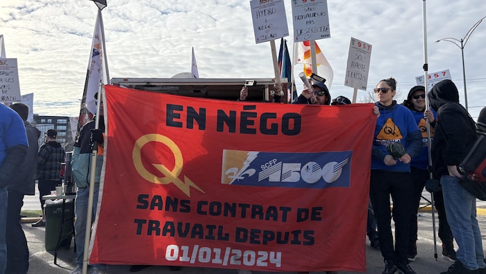 Des travailleurs qui tiennent une grande banderole.