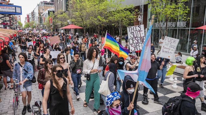 Des manifestants circulent dans la rue en brandissant des pancartes.