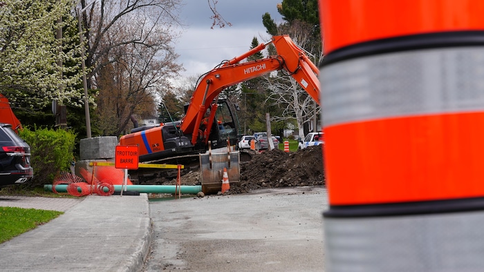 Le trottoir de la 18e Rue est barré. Une pelle mécanique creuse dans le sol.