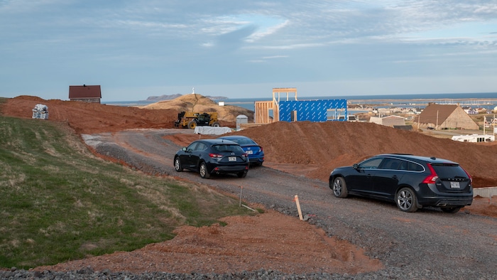 Des voitures sur un chantier de construction avec des tas de terre rouge.