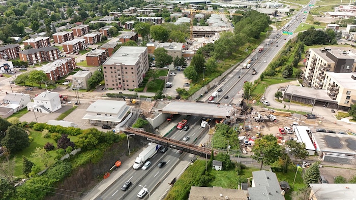 Vue par drone d'un chantier sur le chemin Sainte-Foy. Des véhicules circulent sous une nouvelle structure d'un viaduc en construction au-dessus de l'autoroute Henri-IV. De part et d'autre de l'autoroute, on compte plusieurs tours d'habitation. 