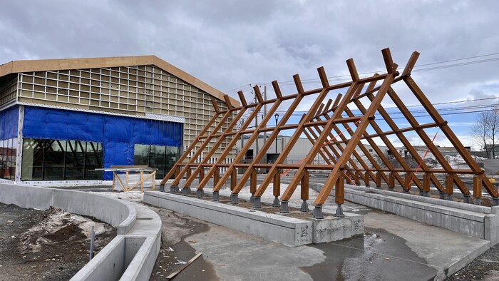 Une structure de shaputuan en bois est érigée devant un bâtiment en construction. 