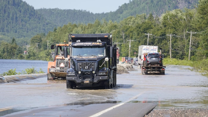 Des camions traversent une voie routière inondée