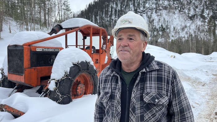 Un travailleur parle devant un tracteur dans la neige.