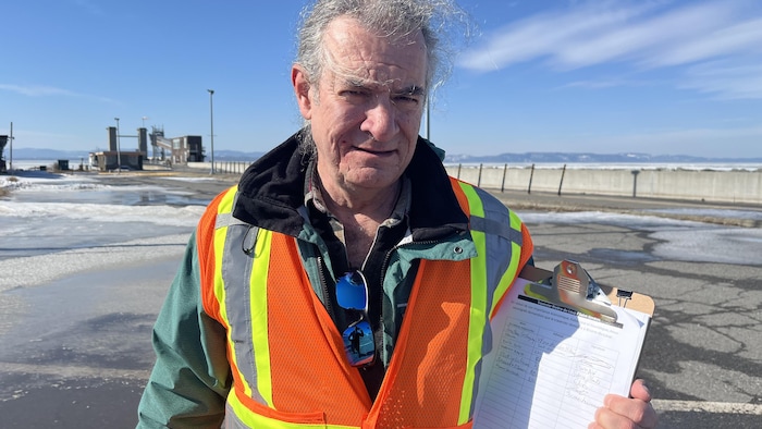 Marc Morin tient sa pétition sur laquelle apparaissent plusieurs signatures alors qu'il est debout au quai de Rivière-du-Loup.