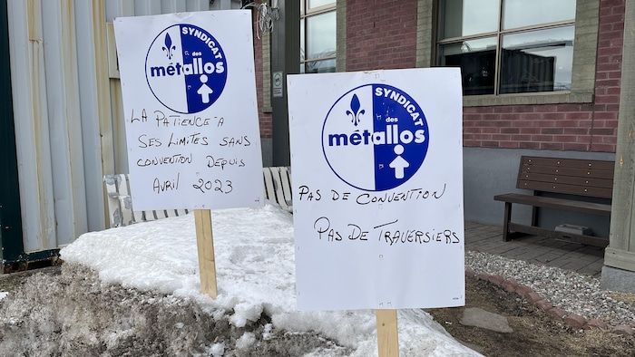 Deux pancartes d'un syndicat sont plantés dans un banc de neige.