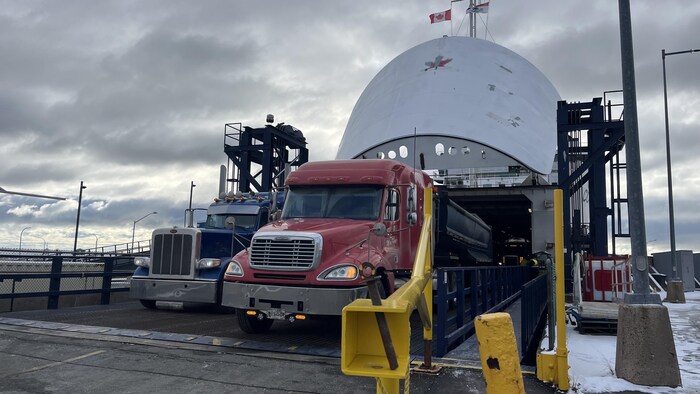 Des camions-remorques sortent du navire.
