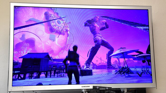 Sur un écran de télévision, une version virtuelle du rappeur Travis Scott danse. 
