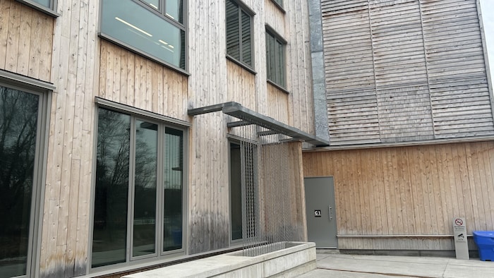 Un immeuble en bois avec un système de récupération d’eau fait de chaines en métal.